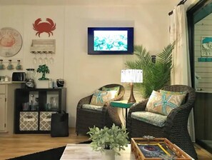 A living room with wicker furniture, a television, and a small table with a plant. - Beautiful Bayfront Water View (Corpus Christi)