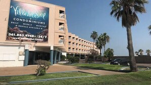 A building with a large billboard advertising Villa del Sol Condominiums, featuring daily, weekly, and monthly rentals.