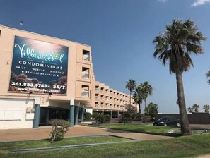 A building with a large billboard advertising Villa del Sol Condominiums, featuring daily, weekly, and monthly rentals.