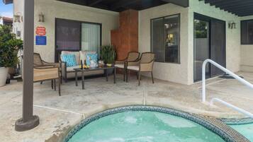A pool area with a hot tub, outdoor seating, and a covered patio.