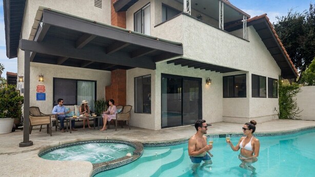 Une maison moderne dotée d’une piscine, d’un espace salon extérieur et d’un patio couvert.