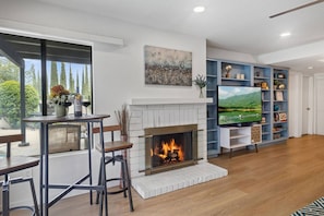 Una sala de estar con chimenea, televisión y estantería.