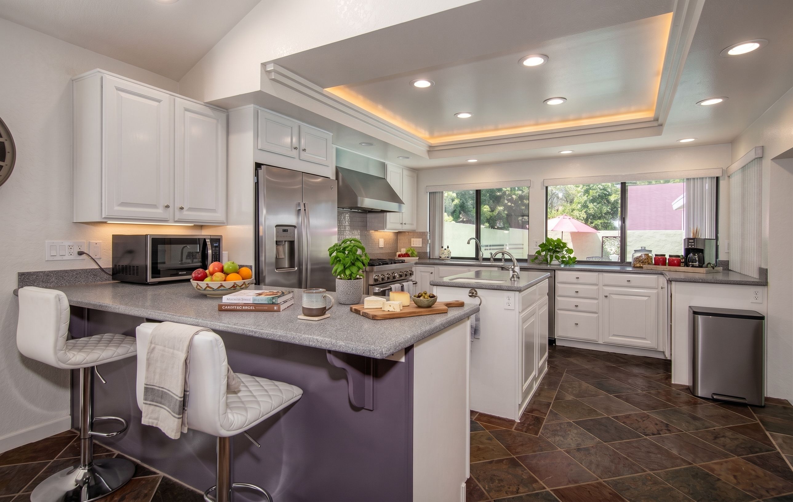 A modern kitchen with a central island, stainless steel appliances, and a large window providing natural light.
