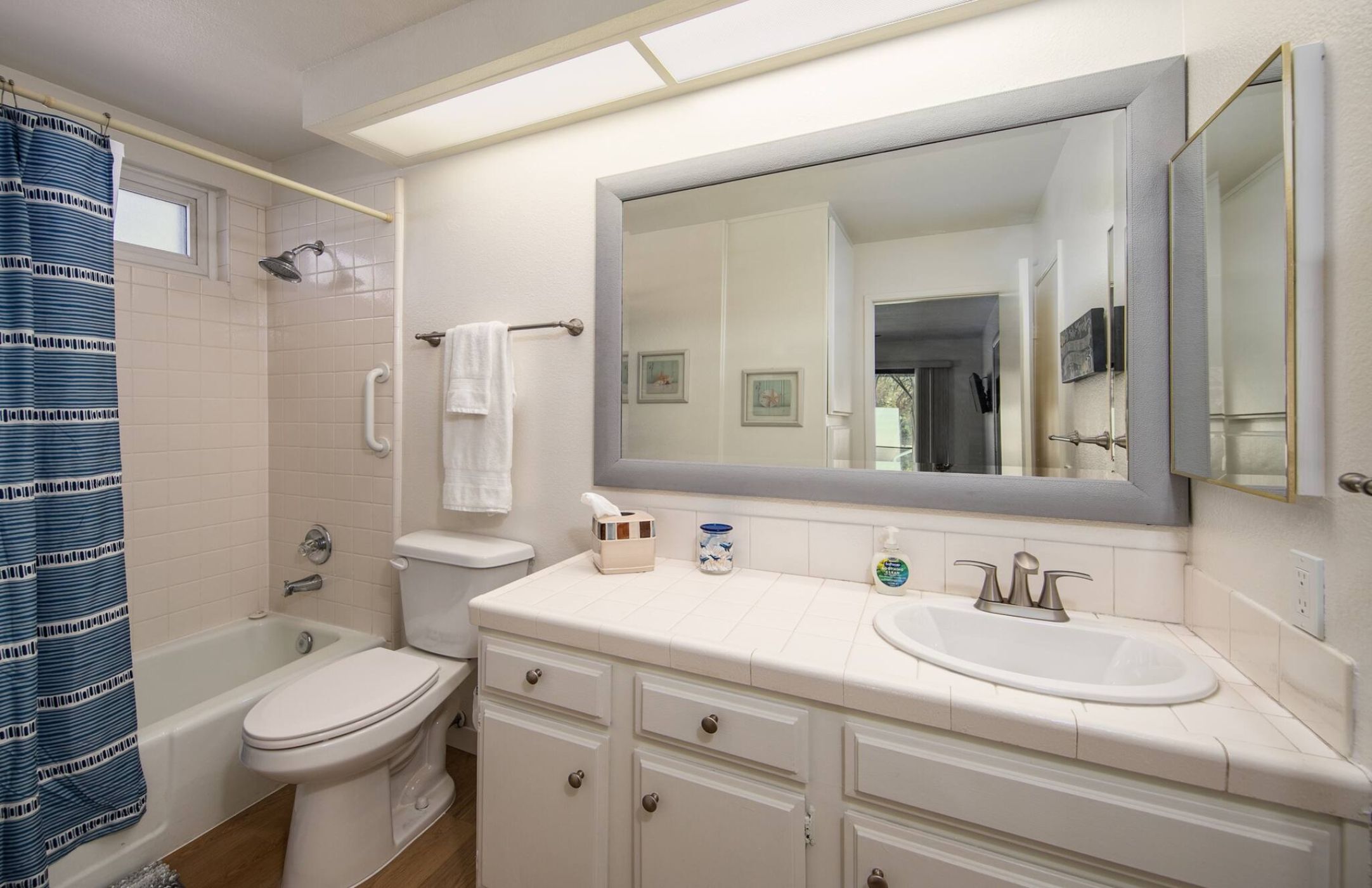 A bathroom with a bathtub, toilet, sink, and a large mirror.