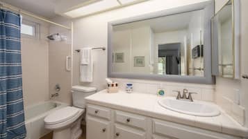 A bathroom with a bathtub, toilet, sink, and a large mirror.
