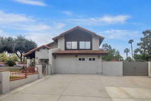 Una casa de dos pisos con techo plano, garaje y patio cercado.