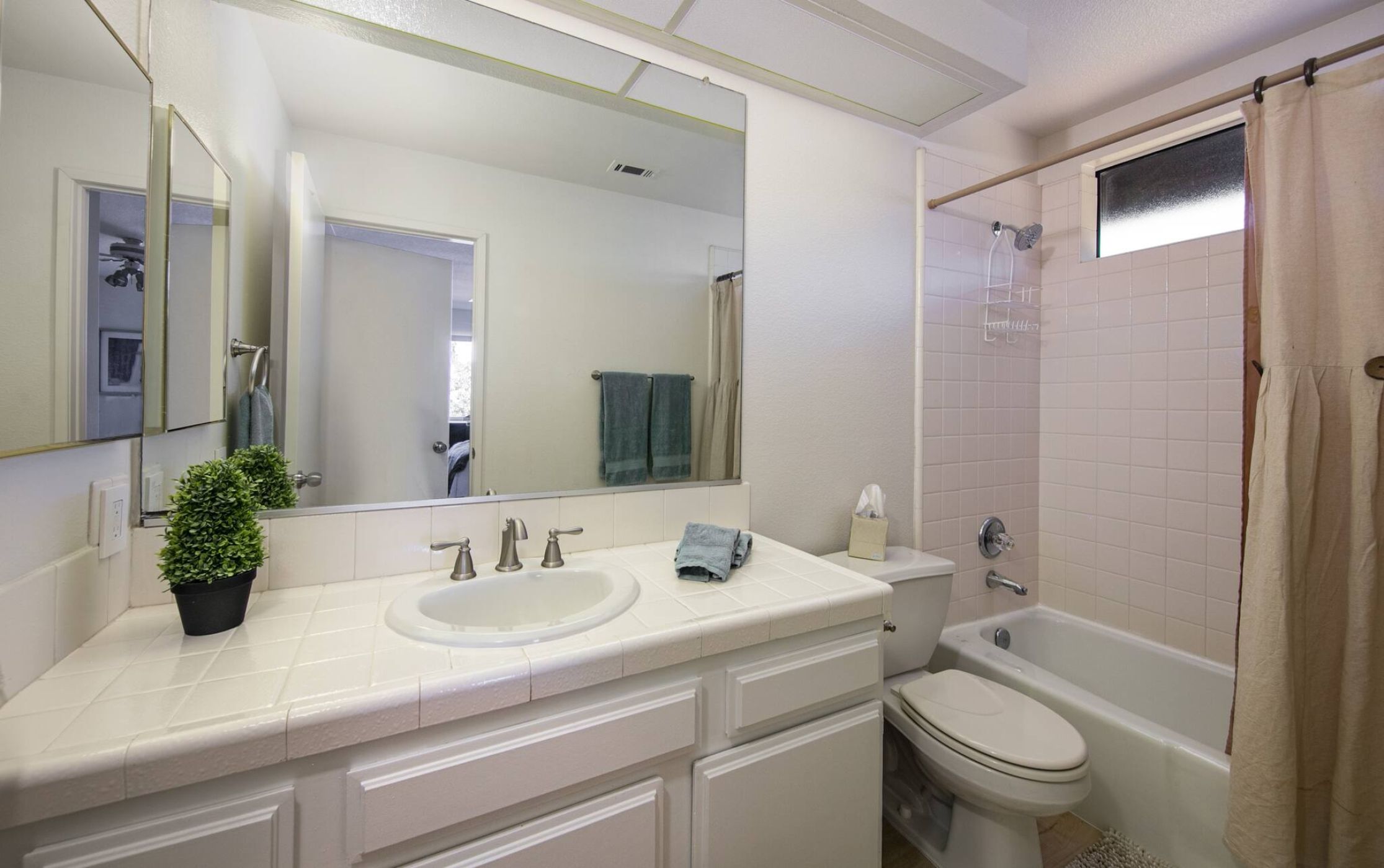 A bathroom with a sink, mirror, toilet, and bathtub.