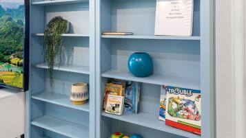A room with a blue shelving unit containing books, decorative items, and a television.