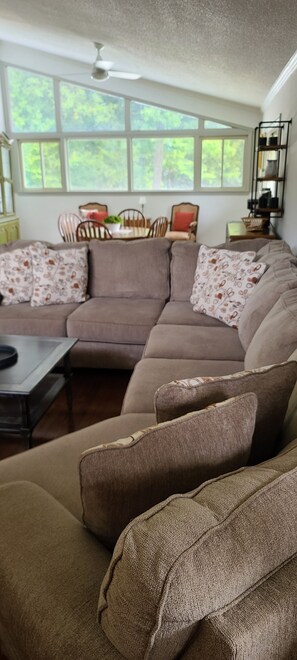 A living room with a sectional sofa, a coffee table, and a dining area with chairs and a table. - Mid-Century Family Home - Corporate Relocatio  Rental (Charlotte)
