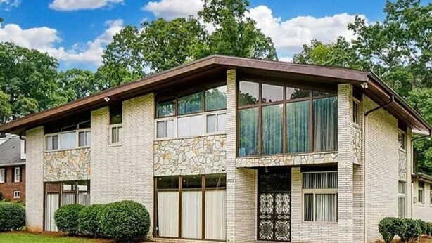 A two-story building with a stone facade, large windows, and a flat roof. - Mid-Century Family Home - Corporate Relocatio  Rental (Charlotte)