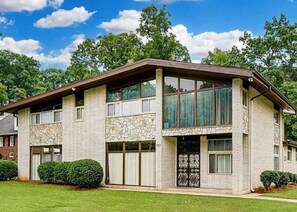 A two-story building with a stone facade, large windows, and a flat roof. - Mid-Century Family Home - Corporate Relocatio  Rental (Charlotte)