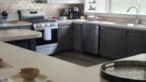 A modern kitchen with a central island, pendant lighting, and a view of the dining area. - Mid-Century Family Home - Corporate Relocatio  Rental (Charlotte)