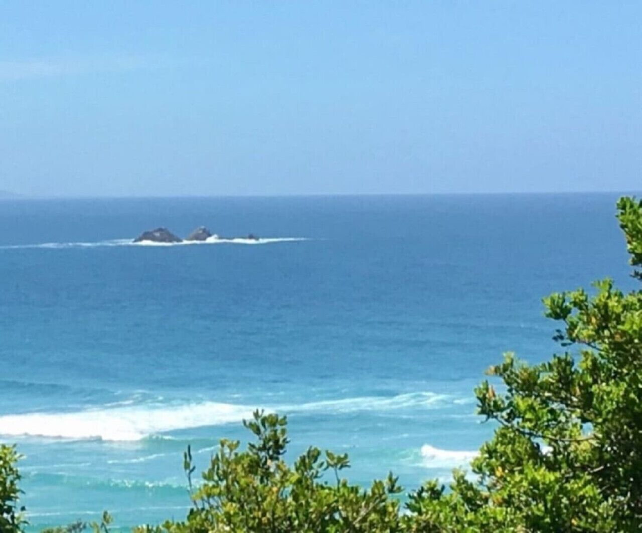 Une vue sur la côte, avec une eau d’un bleu limpide et des reliefs qui se dessinent à l’horizon.