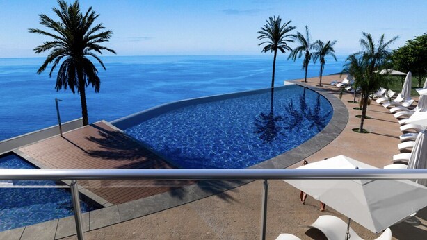 A pool with a curved edge, palm trees, and lounge chairs along a seaside view. - The Stylish Apt. of Madeira Palace CC (Funchal)