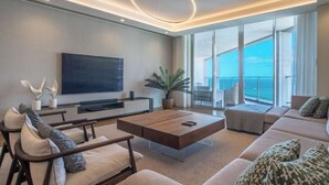 A modern living room with a large flat-screen TV, a wooden coffee table, and a sofa with patterned cushions. - The Stylish Apt. of Madeira Palace CC (Funchal)