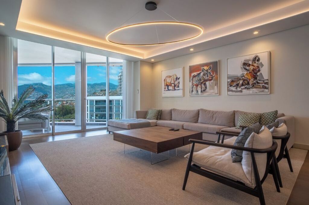 A modern living room with a sectional sofa, a coffee table, and artwork on the wall.
