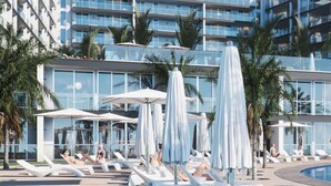 A modern hotel with a pool area, sun loungers, umbrellas, and palm trees. - The Stylish Apt. of Madeira Palace CC (Funchal)