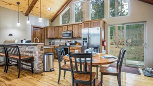 Une cuisine spacieuse avec des meubles en bois, un îlot central en pierre et une grande table à manger avec des chaises.