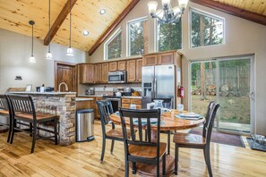 Une cuisine spacieuse avec des meubles en bois, un îlot central en pierre et une grande table à manger avec des chaises.