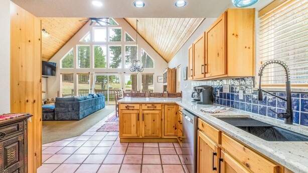 A kitchen with wooden cabinets, a large island, a sink, and a view of the outdoors. - Dog Friendly w/Guesthouse, Deck w/Grill, Foosball, Trail Access, Kid's Playhouse (Angel Fire)