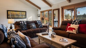 A cozy living room with two brown leather sofas, a wooden coffee table, and a large painting on the wall. - Spacious Townhouse, Firepit, Walkable to Park/Golf/Tennis, Foosball, Two Decks (Angel Fire)