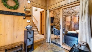 A wooden interior with a stone wall, a bench, a coat rack, and a staircase leading to a bedroom with a stone fireplace. - Spacious Townhouse, Firepit, Walkable to Park/Golf/Tennis, Foosball, Two Decks (Angel Fire)