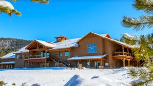 A large, multi-story lodge with a wooden exterior and multiple balconies, surrounded by snow and pine trees. - Spacious Townhouse, Firepit, Walkable to Park/Golf/Tennis, Foosball, Two Decks (Angel Fire)