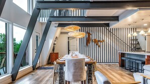 A modern dining area with a long table, chairs, and hanging pendant lights. - Modern Lodge w/Hot Tub, Beautiful View, Foosball, 2 Car Garage, Gourmet Kitchen (Angel Fire)