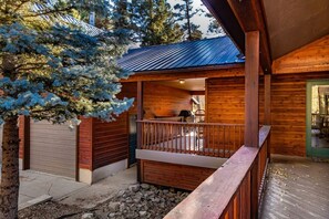 A wooden cabin with a covered porch, a garage, and a dining area.
