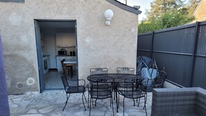 An outdoor patio with a stone floor, a round table with chairs, a covered grill, and a wicker sofa. - Bléré hyper center near Chenonceau and Beauval zoo evening meal possible (Bléré)