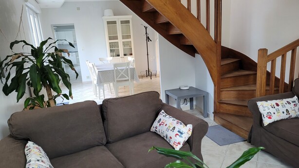 A living room with a brown sofa, a coffee table, and a staircase. - Bléré hyper center near Chenonceau and Beauval zoo evening meal possible (Bléré)