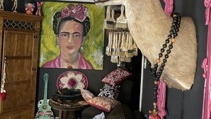 A room with a deer head mounted on the wall, a painting, a guitar, and various decorative items.