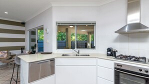 Una cocina moderna equipada con lavavajillas, estufa y ventana con vistas a un jardín.