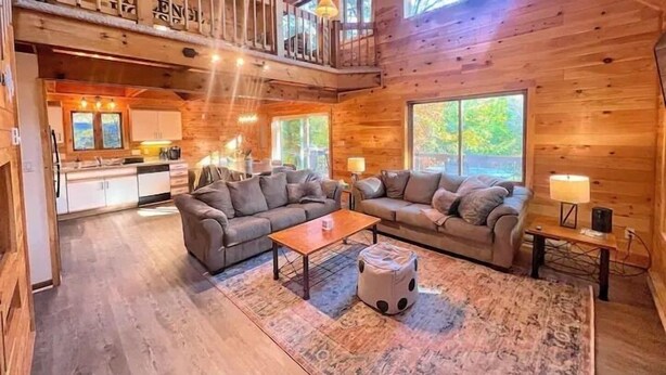 A spacious cabin with a loft bedroom, a cozy living area with two sofas, a dining table, and a kitchen. - The Challenge House-mega games-hottub-beach-lake-The ultimate Poconos game house (Blakeslee)