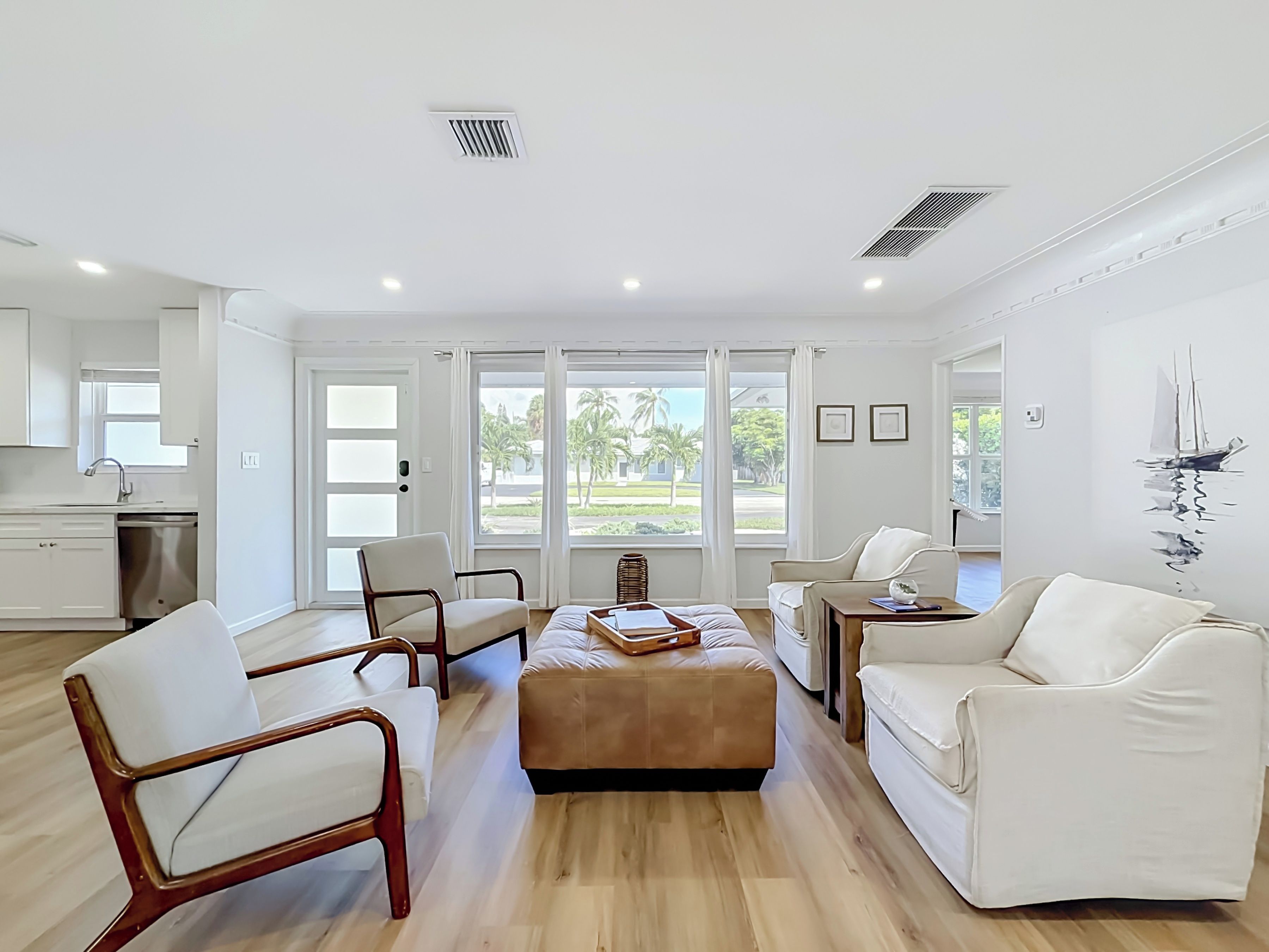 Una sala de estar moderna con un sofá, sillas, una mesa de centro y vistas al exterior a través de ventanas amplias.