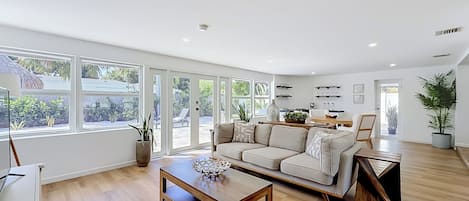 A spacious living room with a large sofa, a wooden coffee table, and a dining area with a table and chairs.