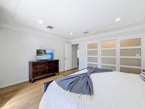 Een slaapkamer met een bed, een televisie op een dressoir en een inloopkast.