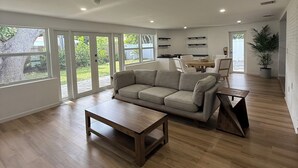 Un salón amplio con un sofá grande, una mesa de centro y una zona de comedor con sillas.