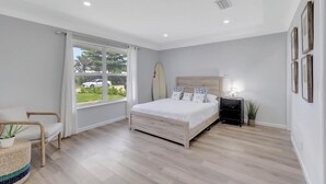 Un dormitorio con cama, una silla, una tabla de surf y una ventana.