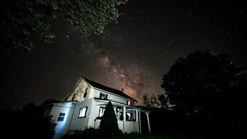 Una casa con porta e finestre ben visibili, circondata da alberi, sotto un cielo stellato.