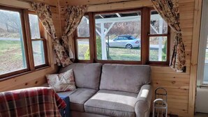 Een gezellige kamer met een bank, gordijnen en uitzicht op een auto.