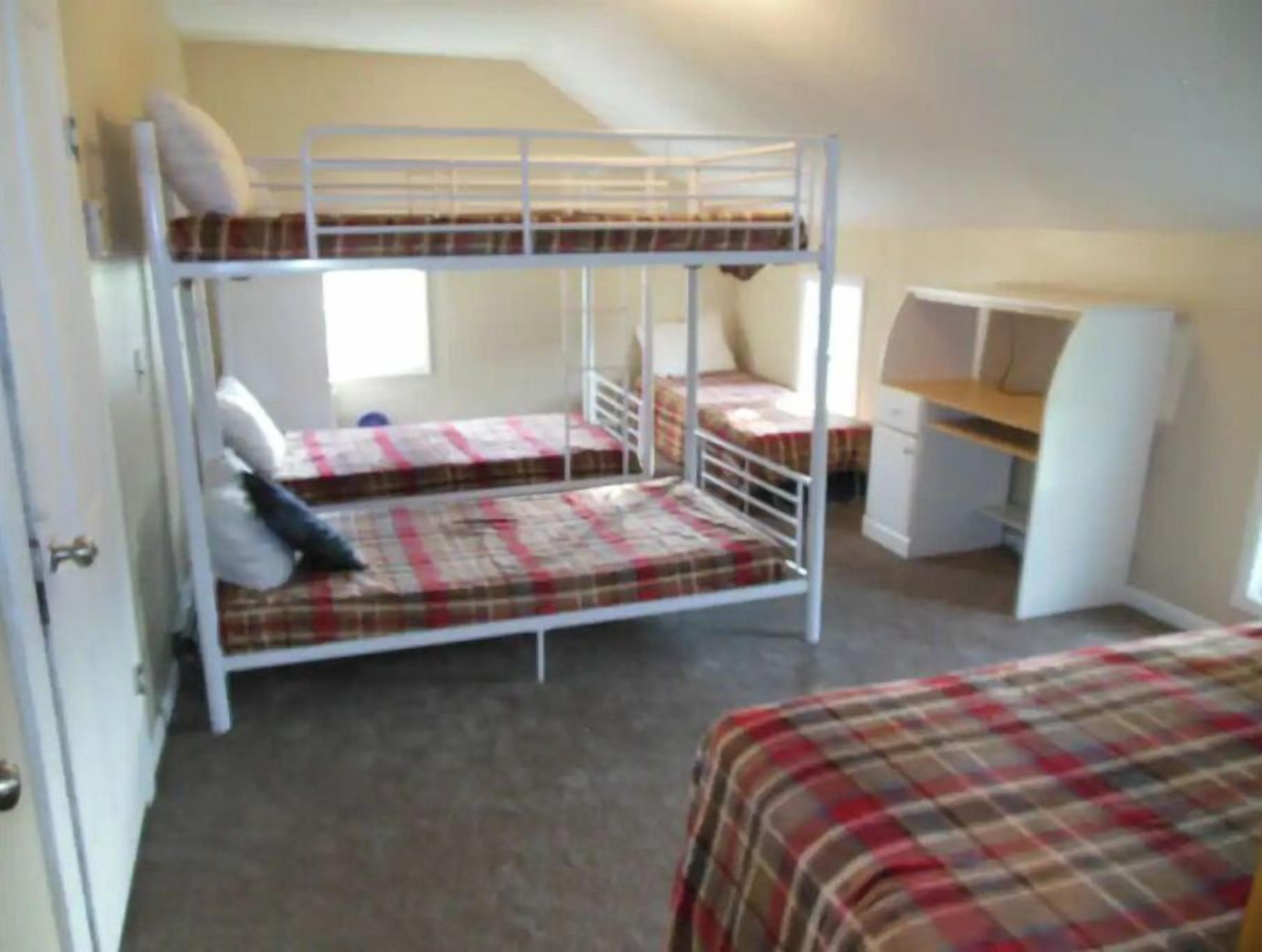 Une chambre de dortoir avec des lits superposés, un bureau et une chaise.