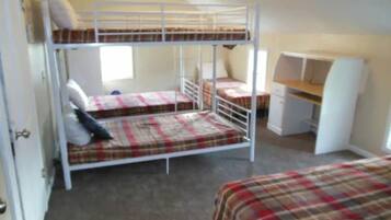 Une chambre de dortoir avec des lits superposés, un bureau et une chaise.