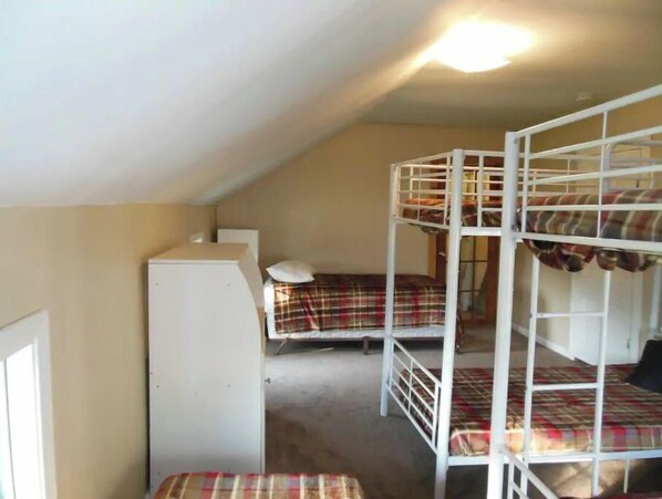 A dormitory room with bunk beds, a white wardrobe, and a ceiling light.