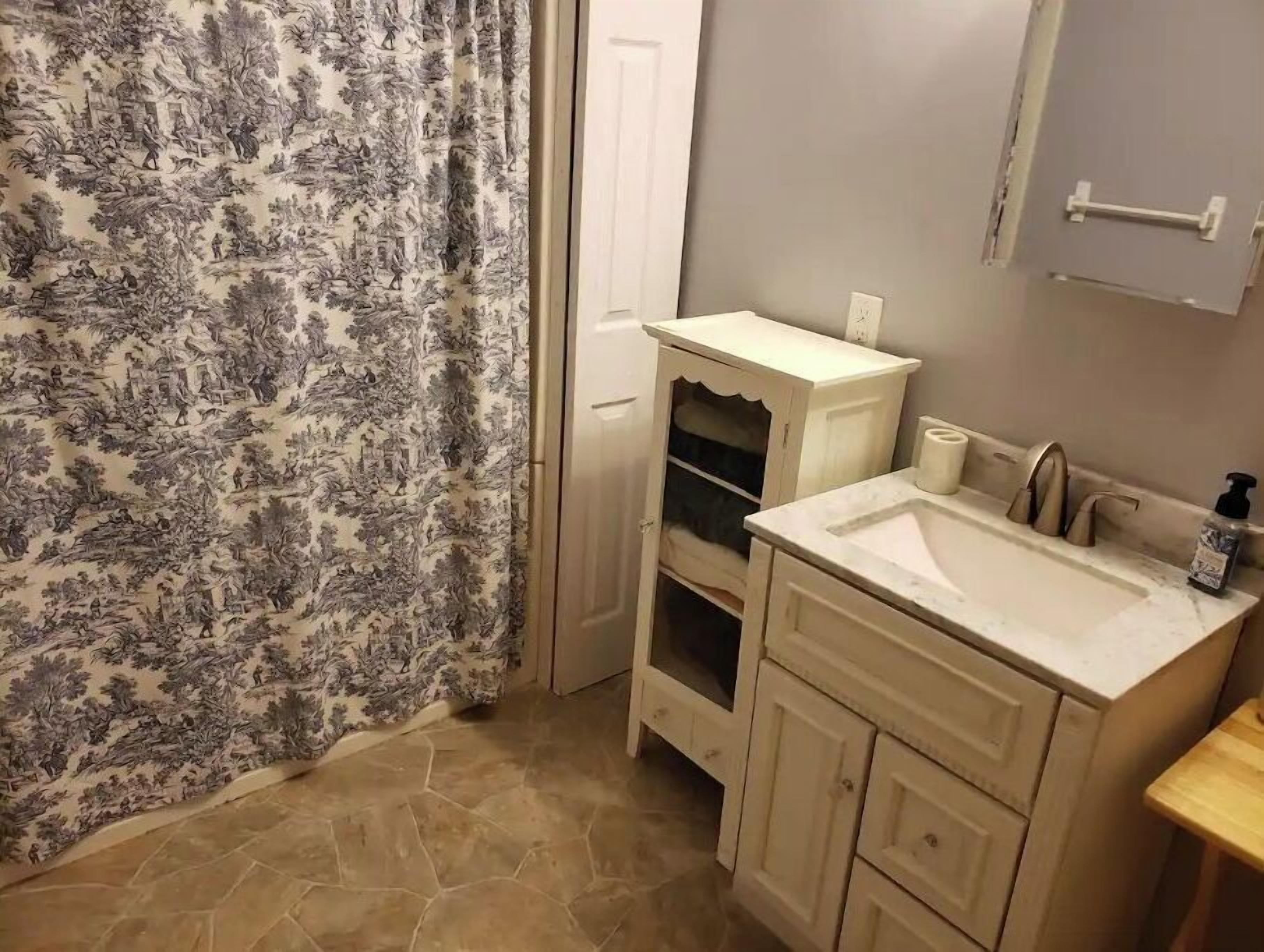Un baño con un lavamanos blanco, un espejo y un armario.