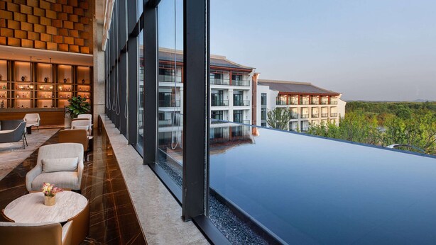 A modern hotel lobby with a large glass window, a reception area, and a poolside view. - Wyndham Grand Plaza Royale Xiangai Mountain Fuzhou (Fuzhou)