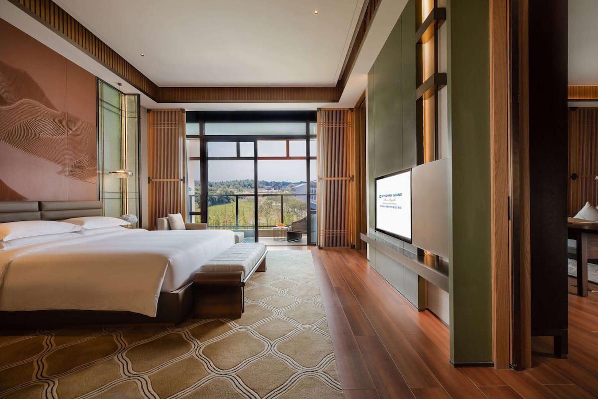 Ein modernes Hotelzimmer mit einem großen Bett, einer Sitzecke und Blick ins Freie.