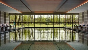 An indoor swimming pool with a clear view of the surrounding forest through large windows. - Wyndham Grand Plaza Royale Xiangai Mountain Fuzhou (Fuzhou)
