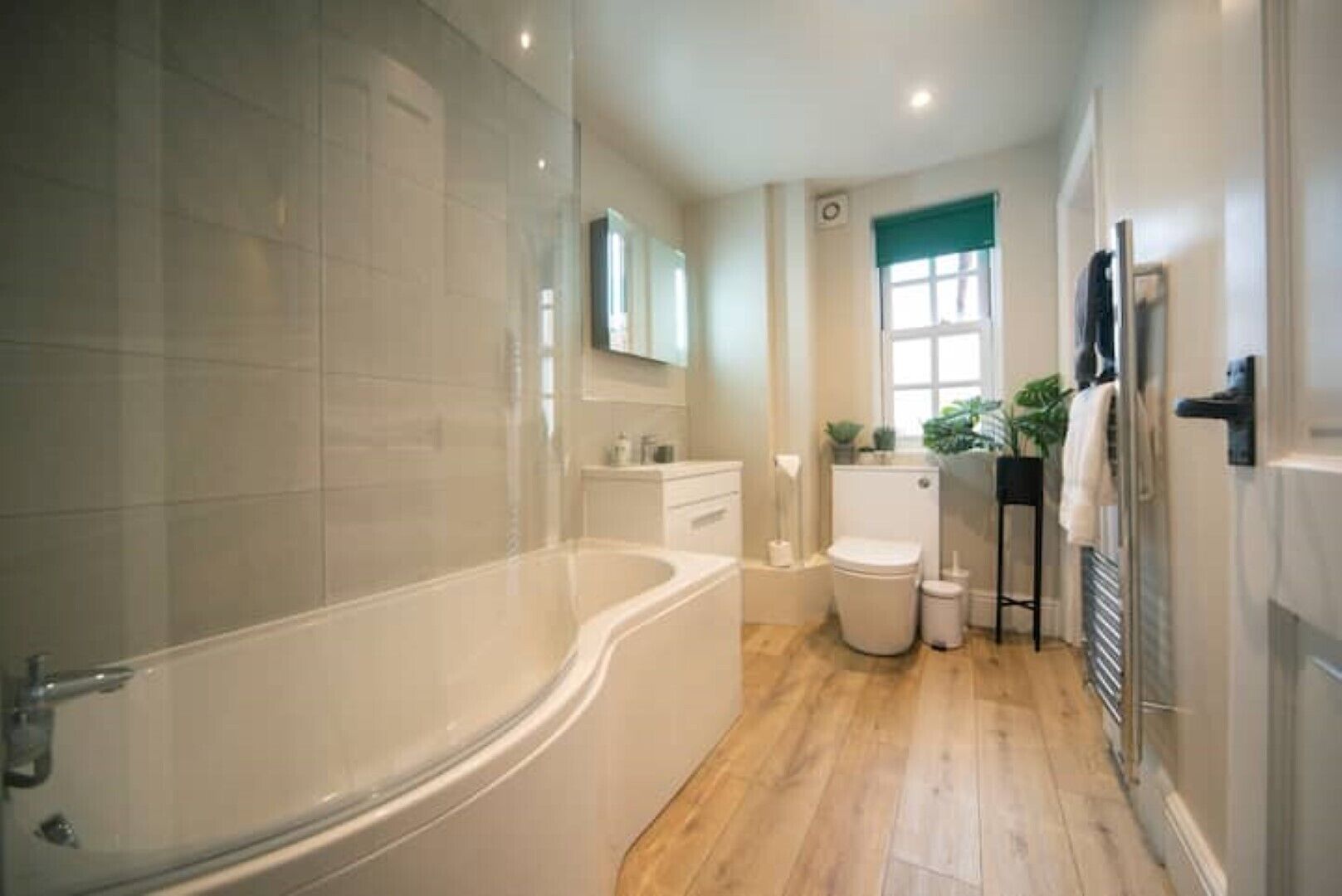 Un bagno con vasca, servizi igienici, lavandino e finestra.