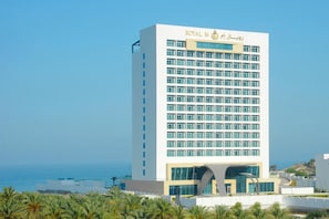 A tall hotel building with a modern design, featuring a prominent entrance and a clear view of the surrounding landscape.